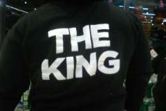 Man from behind wearing hoodie with "THE KING" print inside a store.