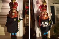 A large nutcracker statue by a doorway at night with a "THE KING" shirt on