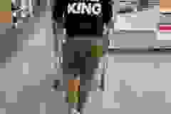 Person in a hoodie labeled "THE KING" pushing a shopping cart in a store.