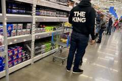 Person shopping in a supermarket aisle with a hoodie that says "THE KING."