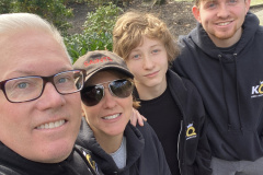 Four people taking a selfie outdoors on a sunny day.