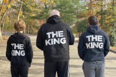 Three people in hoodies labeled "THE KING" standing back to camera.