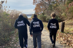 Three people walking on a path with "THE KING" on their jackets.