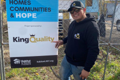 Man smiling by a Habitat for Humanity sign at a construction site.