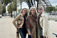 Three women posing in front of the Eiffel Tower.