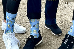 Three people standing close together, one wearing cartoon character socks.