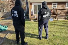 Two people wearing hoodies with "THE KING" text on the back, standing outside.