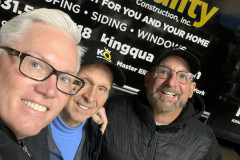 Three smiling men taking a selfie with a King Quality Construction banner.
