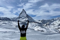Person with arms raised facing the Matterhorn mountain on a clear day.