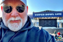 Man in sunglasses and a cap with "Super Bowl LVII" sign in the background.
