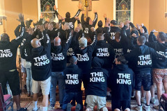 Group of people with raised hands, wearing hoodies with "THE KING" text.