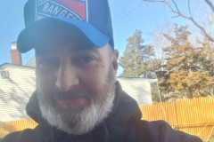 Man in a New York Rangers cap and King Quality hoodie smiling.