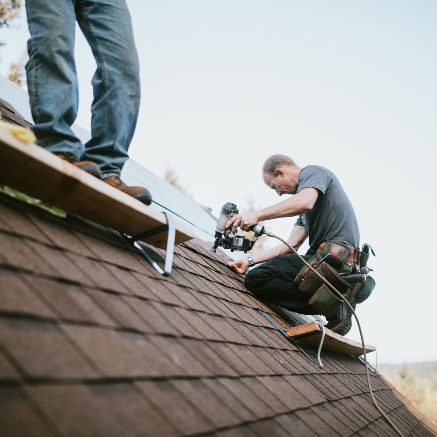 Image of roofer on house with nail gun